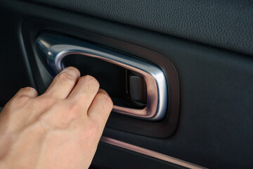 Close up man hand opening a car vehicle door lever or inner door handle is the interior of a modern...