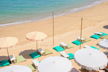 Colorful bean bags with tables and umbrellas on the beautiful sand beach for relaxing holiday at koh larn, Pattaya. Top view of outdoor activity equipment on tropical beach.