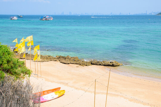 Top view of beautiful tropical beach and crystal clear blue water with kayaks and flags on the beach holiday at Koh Larn island. Amazing view of the sea and beach decorated with summer holiday theme.