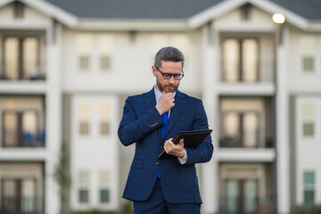 Real estate agent business man in suit hold holder clipboards outside. Hispanic Businessman....