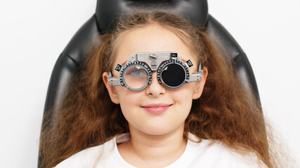 A female doctor uses special glasses to diagnose a patient’s eyes and select lenses in the...