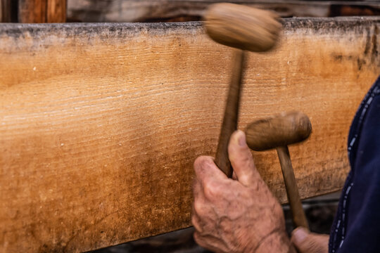 A man using two wooden mallets to beat a wooden semantron. A man using two wooden mallets to beat a wooden semantron