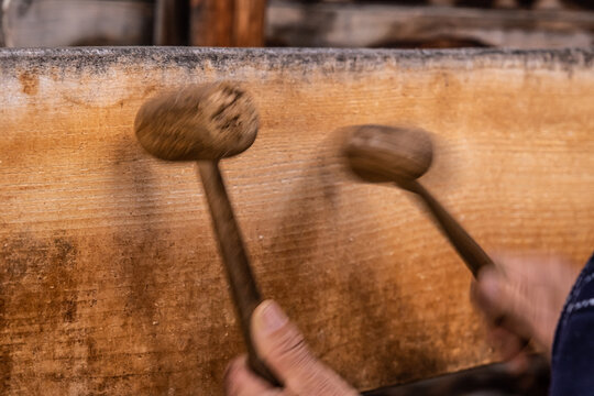 A man using two wooden mallets to beat a wooden semantron. A man using two wooden mallets to beat a wooden semantron