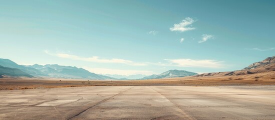 A wide-angle ground with a clear sky and mountainous background for vehicles or products placement. Copy space image. Place for adding text or design