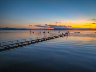 Fototapeta premium Sunrise over the calm water with boats and reflections