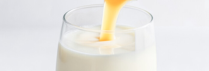 banner close-up of syrup pouring into a glass of milk. free space for text