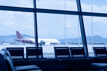 Waiting area with seats in new airport terminal. An airplane taxiing on apron and waiting for flight.