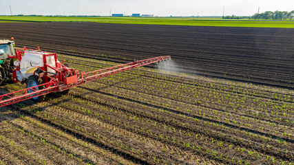 Aerial view on tractor as spraying field with sprayer, herbicide and pesticide