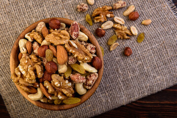 Mixed nuts in wooden bowl on wooden background.