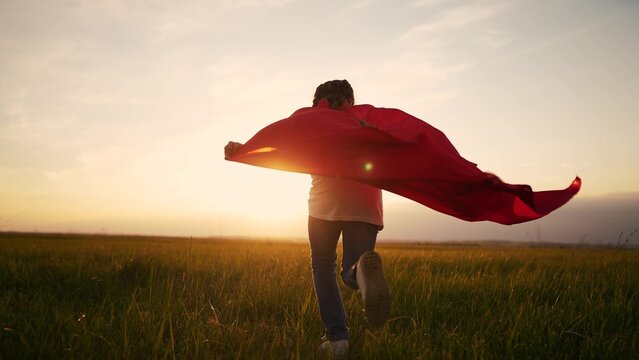 girl superhero. child in a red raincoat runs with a dog lifestyle outdoors in the park. happy family kid dream concept. little girl superhero runs with a dog across the field in nature
