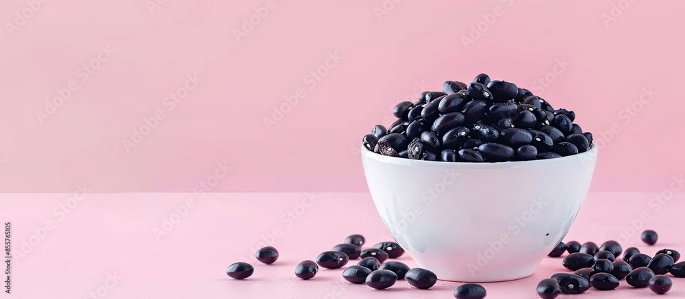 Aufkleber black beans in white ceramic bowl isolated on pastel background. spilled beans. with copy space imag
