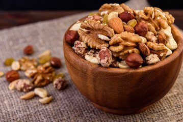 Mixed nuts in wooden bowl on wooden background.