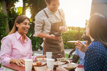 Multiracial people eating at food truck restaurant outdoor during summer time - Dinner and family moments concept Focus on senior woman face