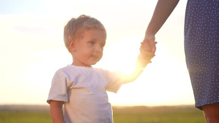 people in the park. mother and son walk at sunset in nature in the summer in the park. happy family a kid dream concept. mother lifestyle and son holding hands in nature. happy family together