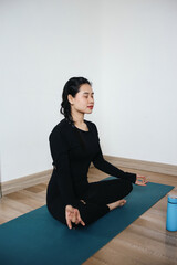 Asian woman meditating with lotus pose at home