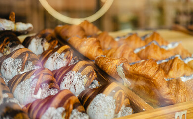 A variety of fresh pastries in the bakery window. Sweet big Croissant on shelf show for sale. Close up of appetizing golden croissants in cafe on shop window.
