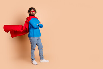 Photo of confident young man wear trendy costume red mask standing empty space isolated on beige color background