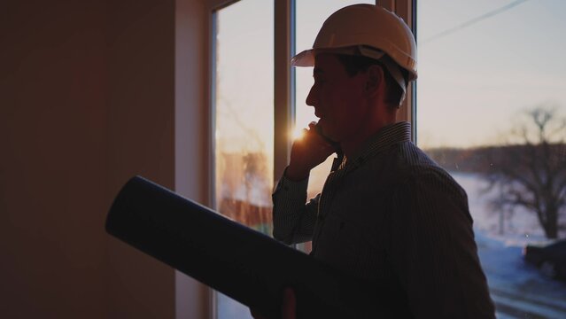 builder silhouette. business building concept. worker in a helmet silhouette idea concept. an engineer in a lifestyle hard hat stands at the window in the house inside the construction site.