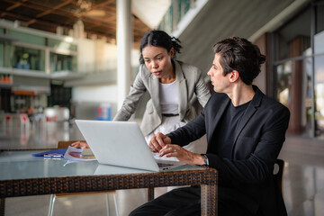 Latino man and African American businessperson brainstorming startup small business strategy together. Young multiracial businesswoman and colleague serious working on planning. Diversity people team.