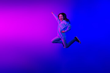 Full length photo of shiny attractive little lady dressed hoodie jumping high hurrying empty space isolated neon pink color background