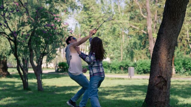 outdoors in a park with trees a young brunette guy with a brunette girl playing bambinton best friends relaxing together the girl serves
