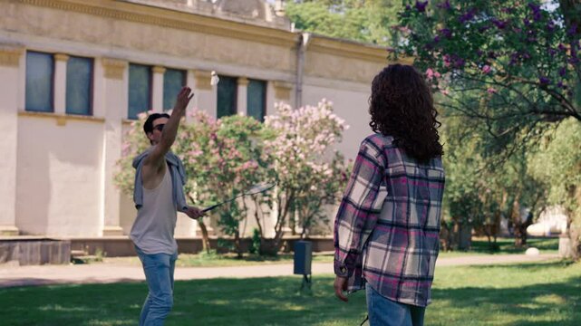 outdoors in a park with trees a young brunette guy with a brunette girl playing bambinton best friends relaxing together the girl serves