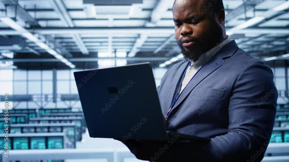 Poster computer scientist in high tech facility using laptop to patch network issues affecting server cabin