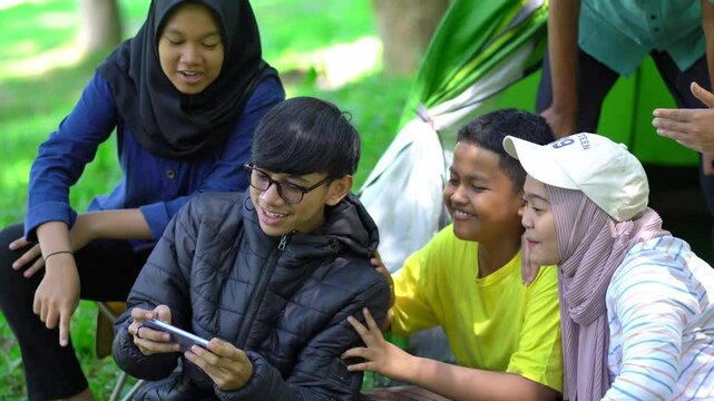 a group of young people playing online games while going camping, relaxing while going camping together.
