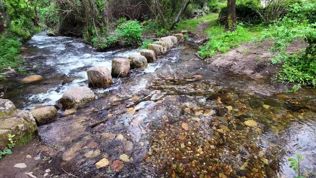 Walking across a bridge of stones over a stream at Percurso Pedestre de Galegos in Portalegre District in Portugal