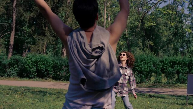 outdoors in a park with trees a young brunette guy with a brunette girl playing bambinton best friends relaxing together the girl serves