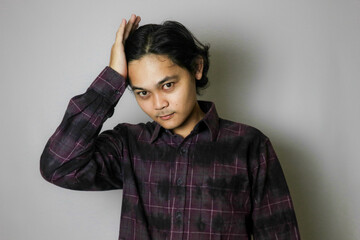 Portrait of an Asian Indonesian young man wearing a purple shirt with a random expression when photographed with an isolated white background