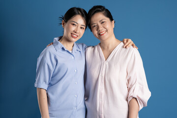 Obraz premium Image of an Asian mother and child posing on a blue background.