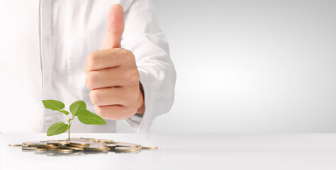 Businessman holding plant sprouting from a handful of coins