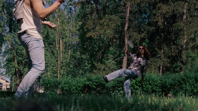 outdoors in a park with trees a young brunette guy with a brunette girl playing bambinton best friends relaxing together the girl serves