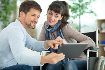 Fototapeta premium couple looking at tablet pc woman is in a wheelchair
