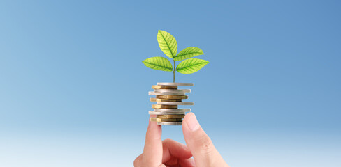 Businessman holding plant sprouting from a handful of coins
