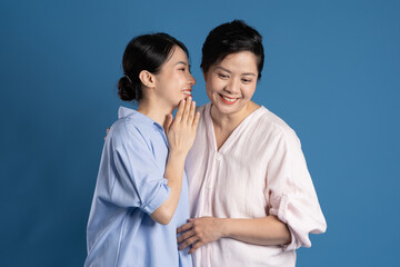 Image of an Asian mother and child posing on a blue background.