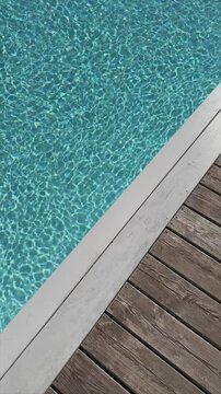 Swimming pool with clear blue water with sunlight shadow reflections on waves. Minimal aesthetic summer vacation concept background with poolside