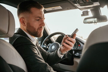 Man in black suit is sitting in the car, driving