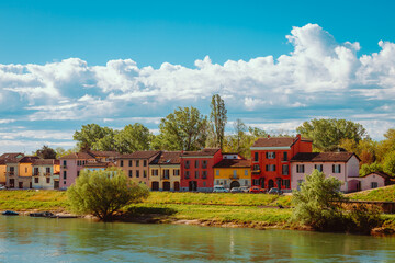 Obraz premium Colorful houses in front of the Ticino River running through the city of Pavia with white clouds in the background