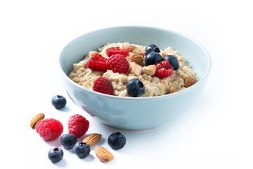 Oatmeal porridge with raspberries, blueberries and almonds in bowl isolated on white background