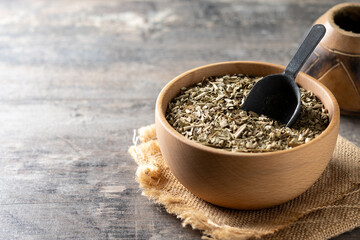 Traditional yerba mate in wooden bowl on wooden table. Copy space