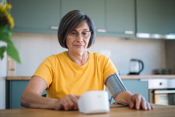 Senior woman measuring blood pressure at home