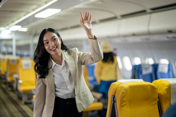 A woman in a business suit is waving to passengers on an airplane