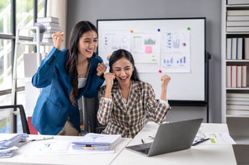 Two women are celebrating in front of a white board with graphs and charts
