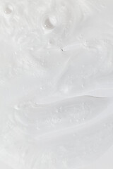 Macro shot of a moisturizer's texture showcasing its smooth, glossy surface with visible swirls and bubbles. This detailed close-up highlights the product's creamy and hydrating properties