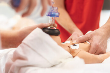 Hands of paramedic of emergency medical service during training resuscitation training on newborn dummy. .