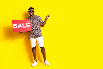 Photo of positive man wear trendy clothes showing placard poster empty space isolated on yellow color background