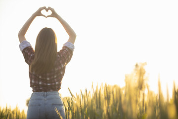 Fototapeta premium woman raises her hands make heart symbol meaning love and friendship on beautiful morning nature landscape background. Concept ​​using hands to make heart symbol represents meaning of friendship love