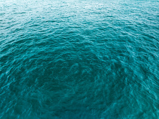 Aerial view of a blue sea surface water texture background,Sun reflections over ocean, Aerial flying drone view Waves water surface texture on sunny tropical ocean in Phuket island Thailand